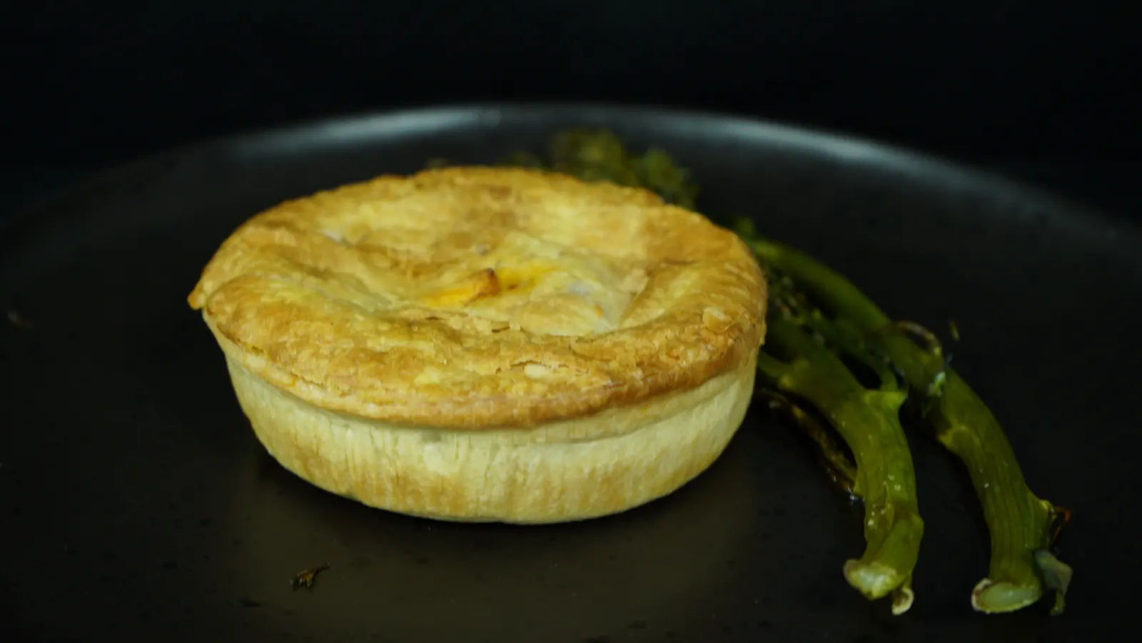 A Nonna Tina's pie on a plate with broccolini